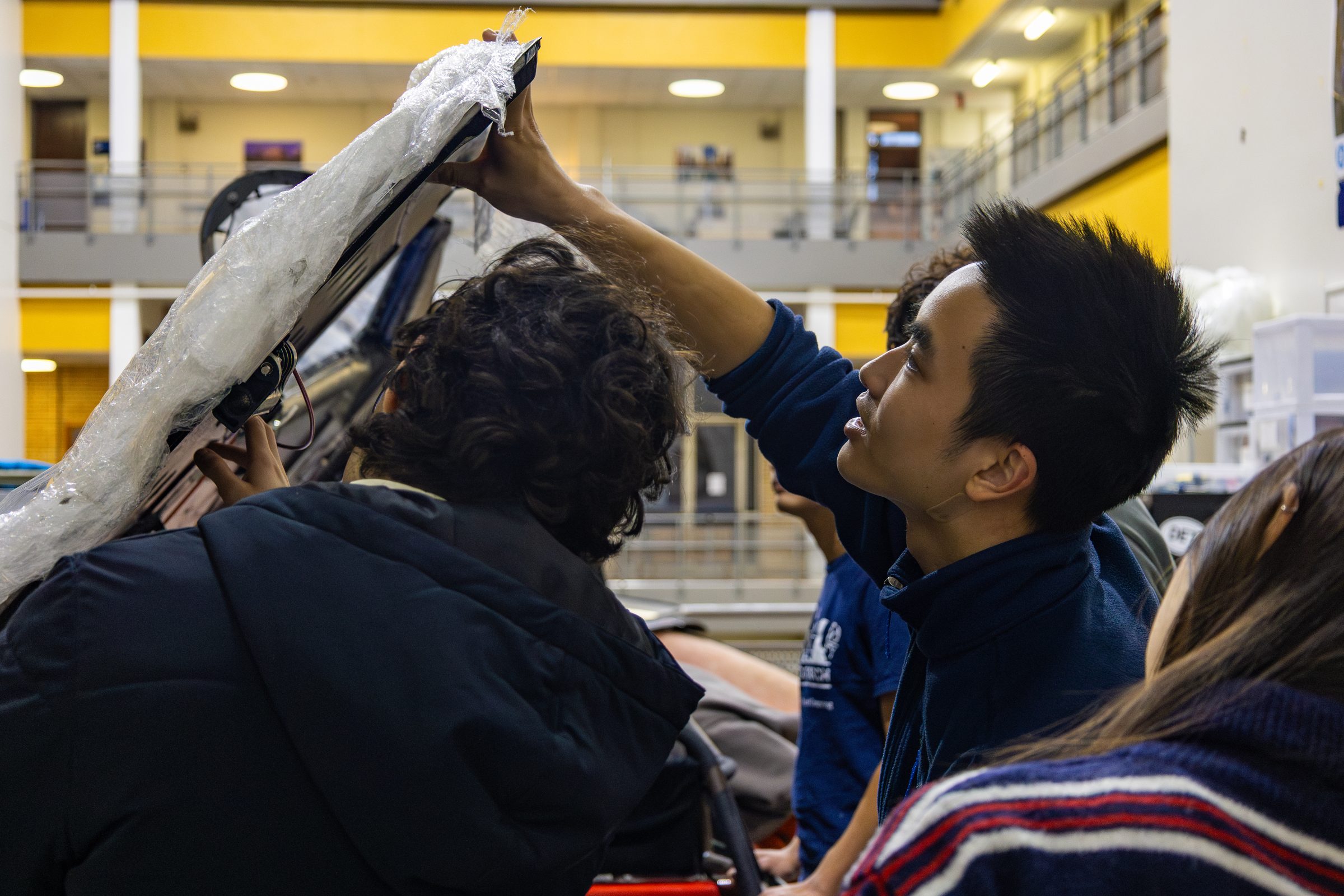 Team members lifting the car's canopy open together