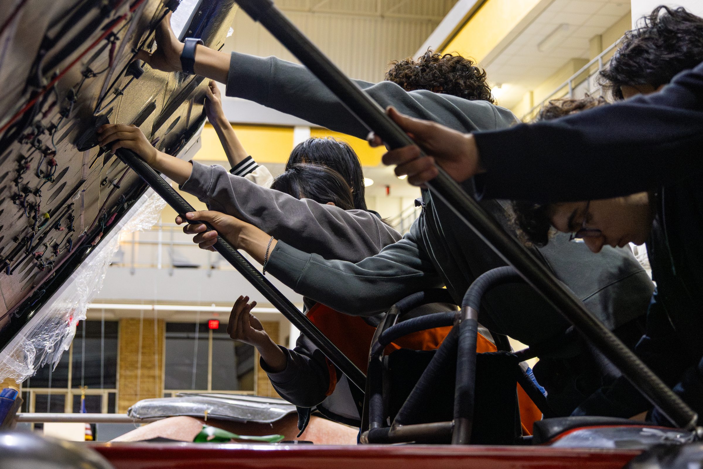 Team members lifting the Carrera solar car's canopy open in the shop