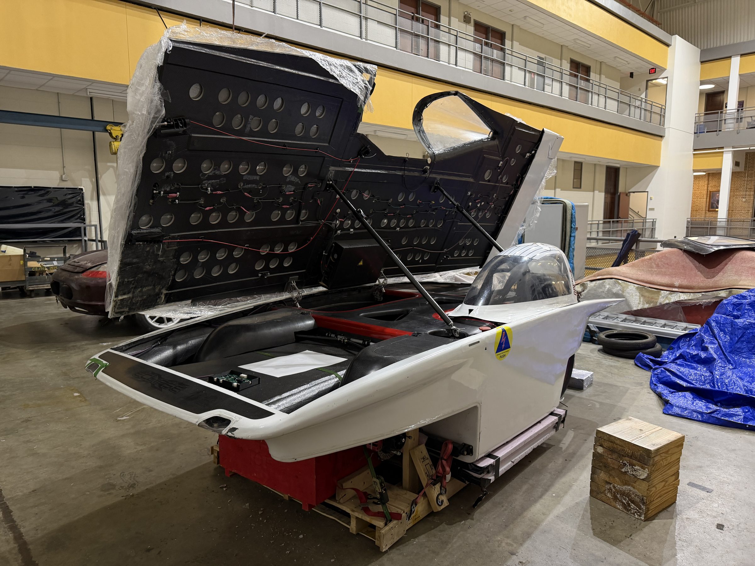 The Carrera solar car's canopy open, front three-quarter view in the shop