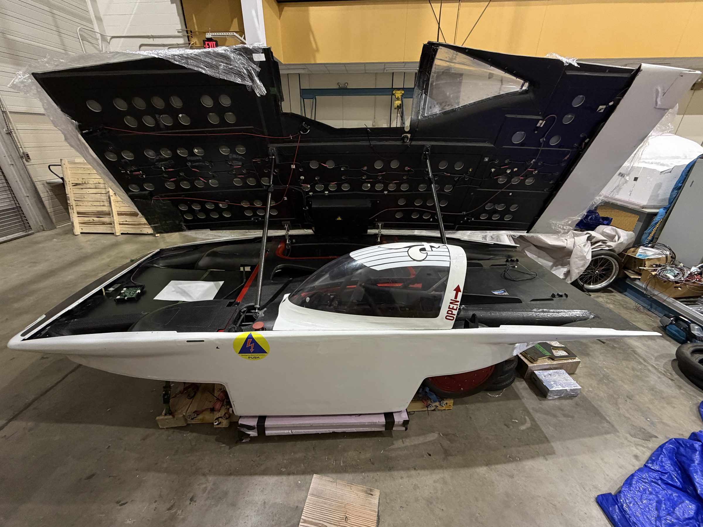 The Carrera solar car with its canopy open, front three-quarter view in the shop