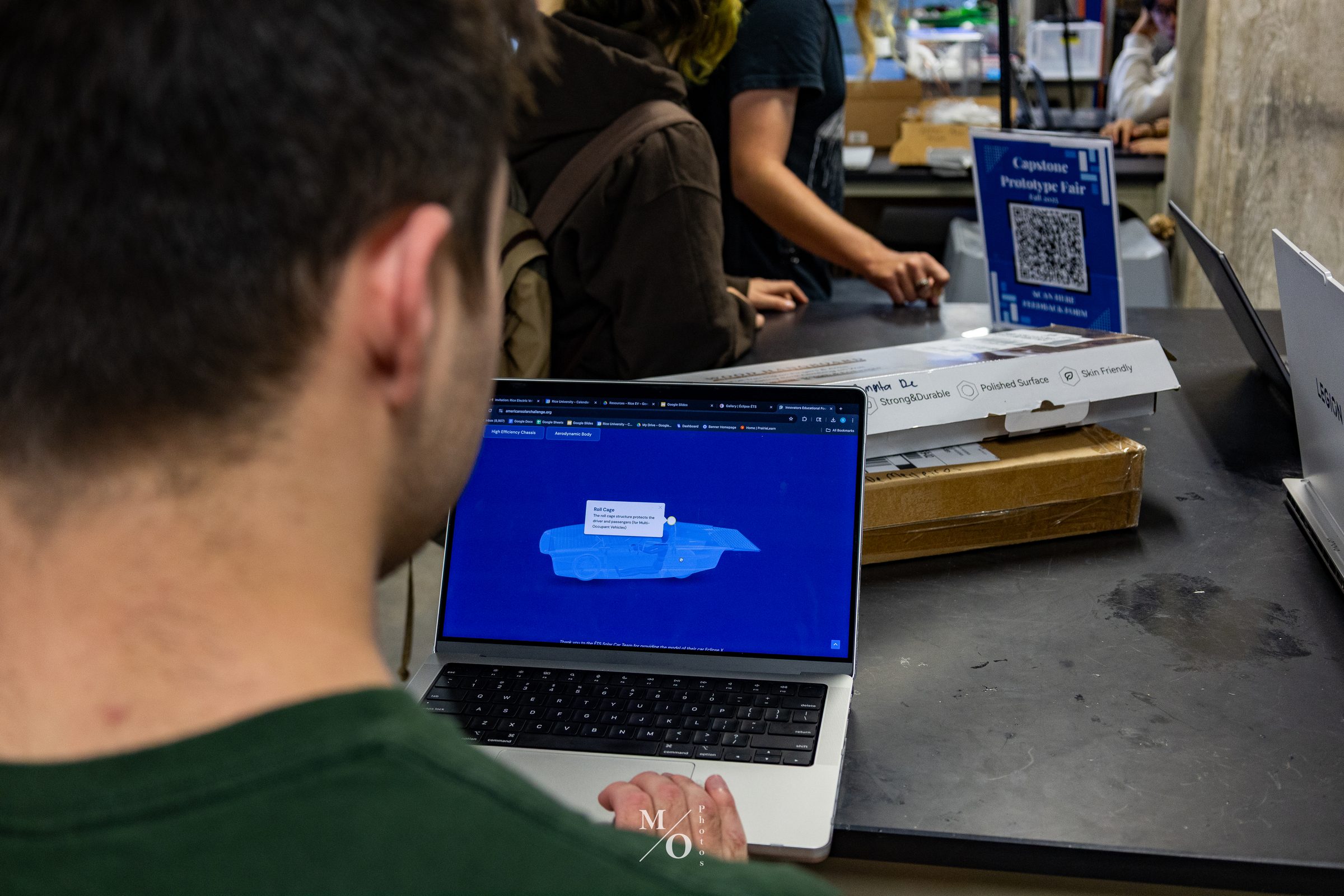Team members reviewing a CAD model of the car on a laptop